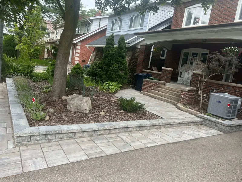 Front-yard landscaping with interlock and gardens